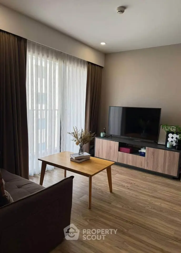 Modern living room with wooden flooring, stylish TV stand, and large window with curtains.