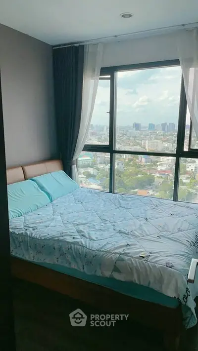Cozy bedroom with large window offering stunning city views, perfect for relaxation and comfort.