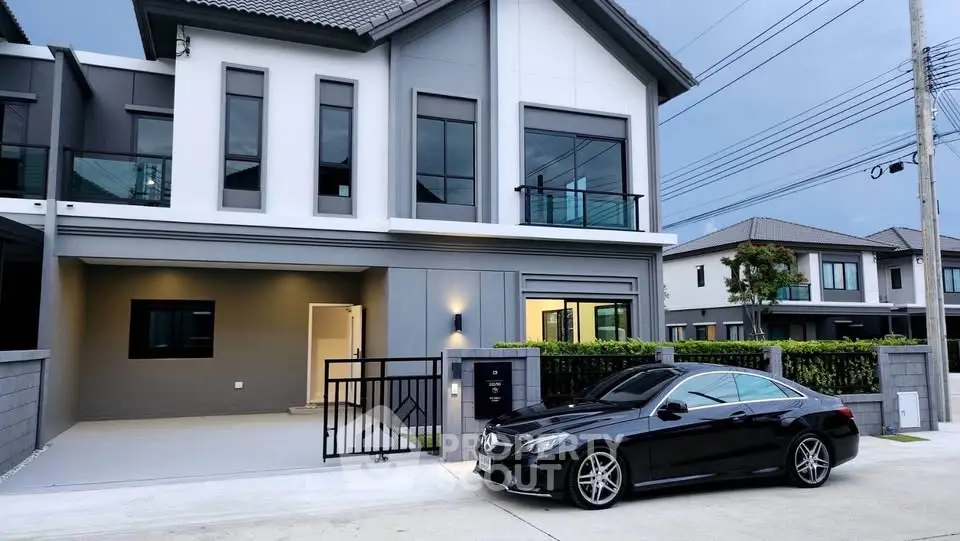 Modern two-story house with sleek design and luxury car parked in driveway, showcasing contemporary architecture.