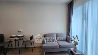 Modern living room with cozy sofa and dining area, featuring elegant decor and natural light.