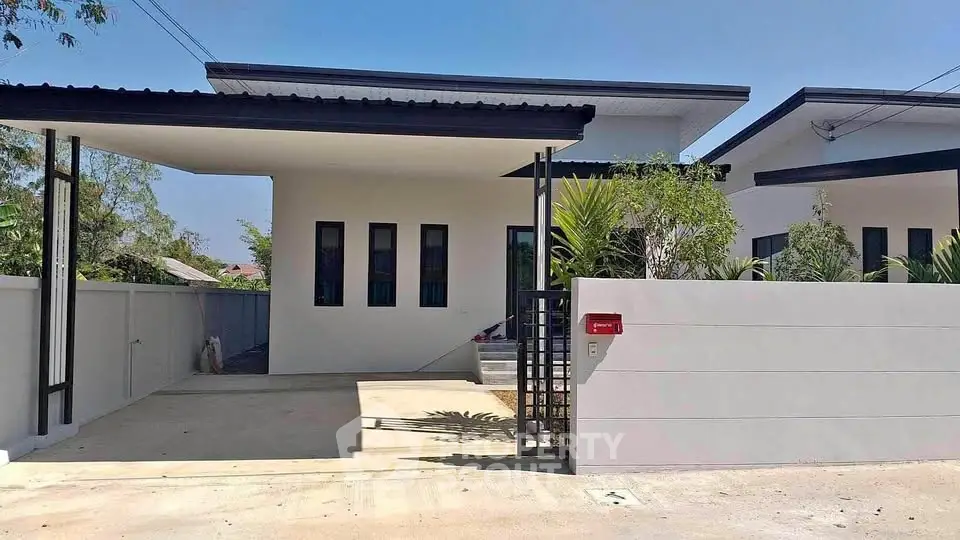 Modern minimalist house exterior with sleek design and gated entrance.
