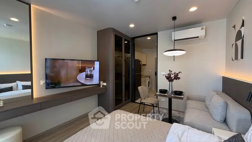 Modern studio apartment with sleek design, featuring a cozy living area, wall-mounted TV, and stylish decor.
