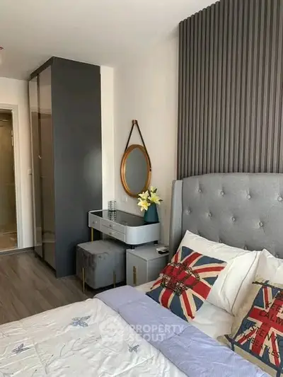 Modern bedroom with stylish decor and Union Jack pillows, featuring a cozy bed and elegant furnishings.
