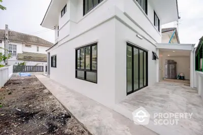 Modern white exterior of a two-story house with large windows and spacious outdoor area.