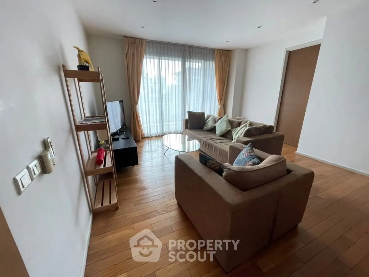 Spacious living room with cozy sofa and natural light, perfect for relaxation.