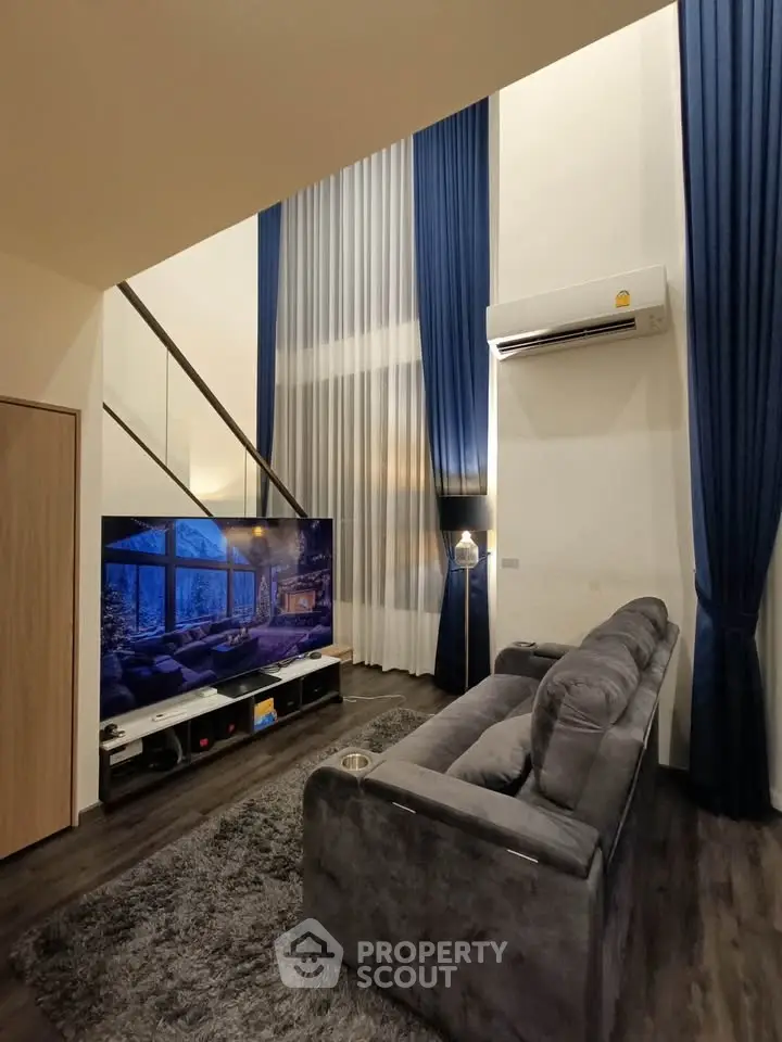 Luxurious high-ceiling living room with modern decor and large TV, perfect for relaxation and entertainment.