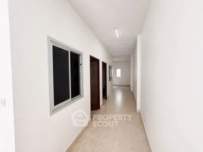 Spacious corridor with tiled flooring and modern lighting in a residential building.