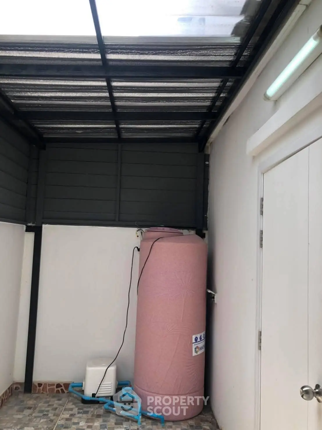 Covered outdoor utility area with water tank and tiled flooring