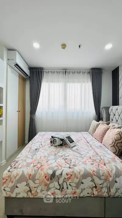 Cozy bedroom with floral bedding, modern decor, and ample natural light from large windows.