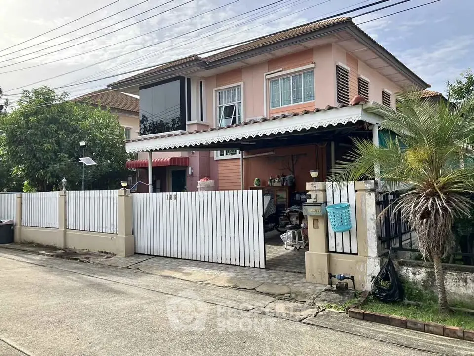 Charming two-story house with gated driveway and lush greenery in a serene neighborhood.