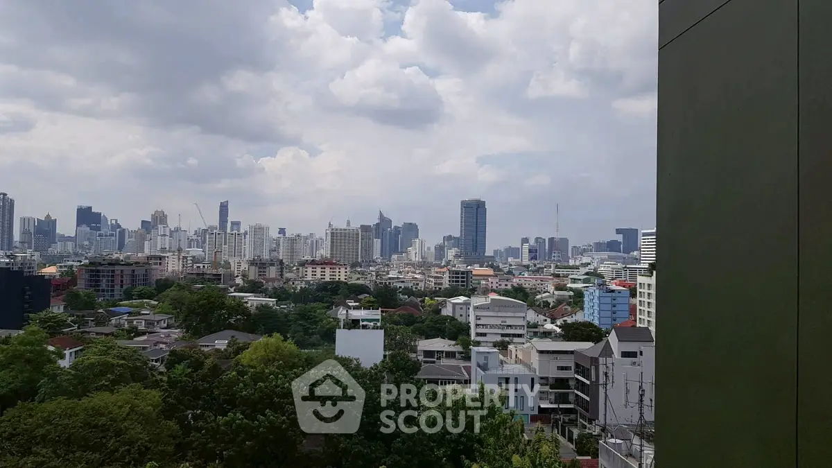 Stunning cityscape view from a high-rise building, showcasing urban skyline and lush greenery.