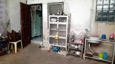 Rustic kitchen area with open shelving and basic amenities in need of renovation.