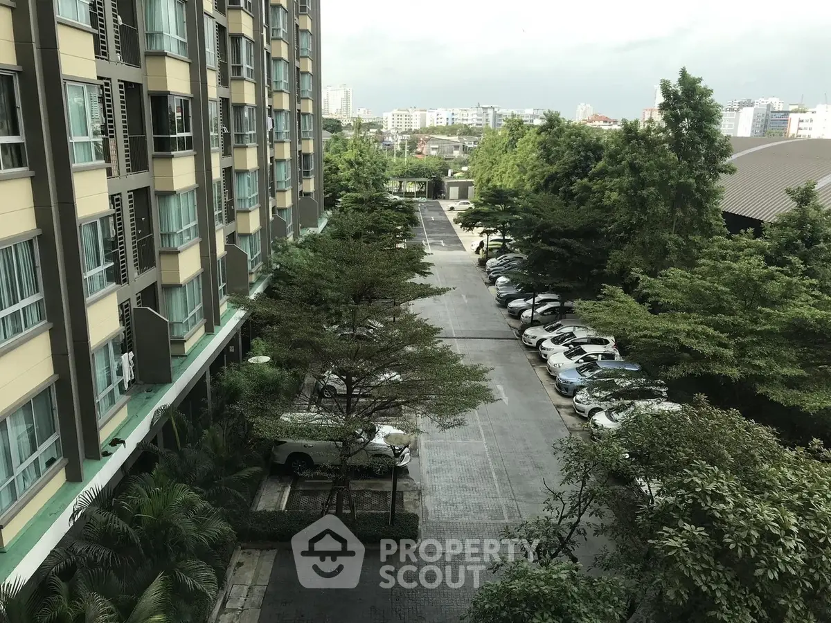 Spacious apartment building with lush greenery and ample parking space in a serene urban setting.