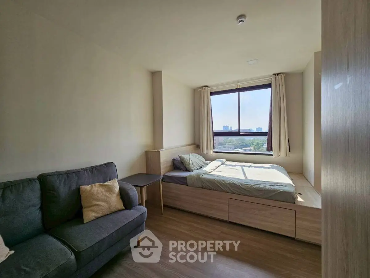 Cozy bedroom with city view, featuring a comfortable bed and stylish sofa.