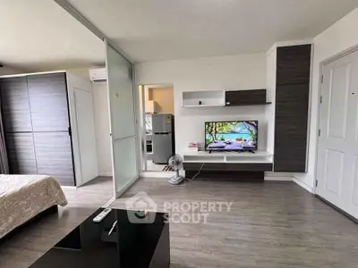 Modern living room with sleek furniture and open layout, featuring a flat-screen TV and stylish decor.