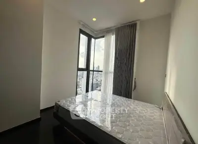 Modern bedroom with large windows offering stunning city views, featuring a comfortable bed and sleek design.