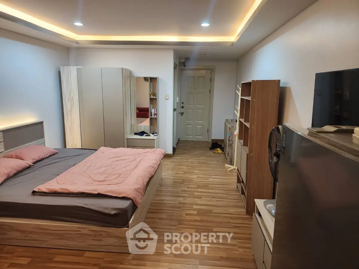 Modern bedroom with stylish lighting and wooden flooring, featuring a cozy bed and ample storage space.