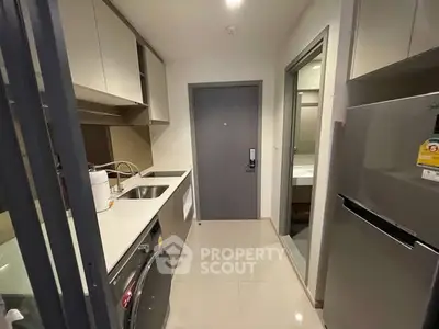 Modern kitchen with sleek appliances and compact design, featuring a washing machine and fridge.