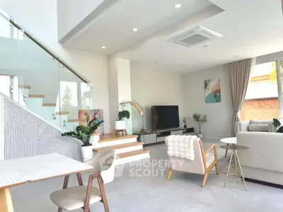 Modern living room with stylish furniture and natural light, featuring a staircase and contemporary decor.