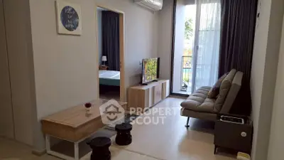 Modern living room with natural light, stylish furniture, and a view of the bedroom and balcony.