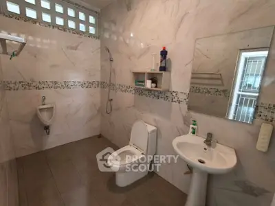 Spacious modern bathroom with elegant tile design and essential fixtures.