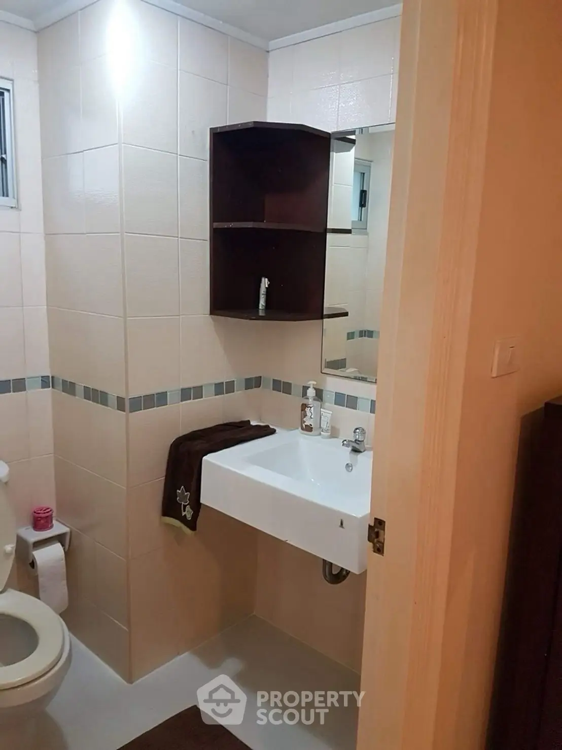 Cozy bathroom with modern fixtures and neutral tiles, featuring a sleek sink and ample storage space.