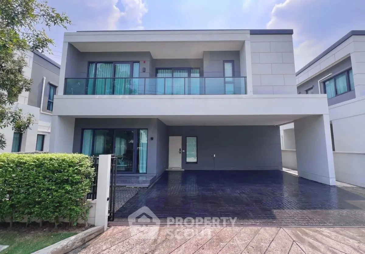 Modern two-story house with spacious driveway and sleek balcony design.