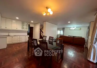 Spacious open-plan living and dining area with elegant wooden flooring and modern lighting.