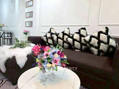 Stylish living room with plush sofa and floral decor, perfect for modern interiors.