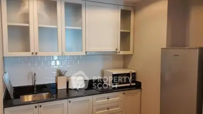 Modern kitchen with sleek cabinetry, microwave, and fridge in a stylish apartment.