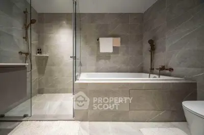 Luxurious modern bathroom with elegant gray tiles and spacious bathtub.