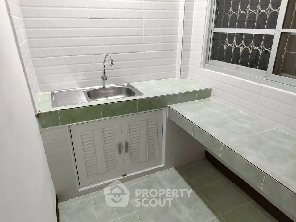 Compact kitchen with green tile countertops and stainless steel sink