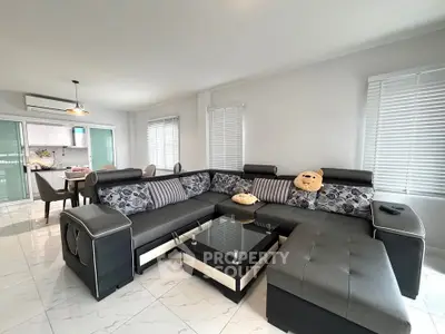 Spacious modern living room with stylish sectional sofa and open kitchen layout.