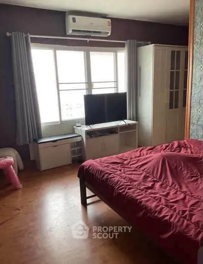Cozy bedroom with natural light, featuring a TV and air conditioning, perfect for relaxation.