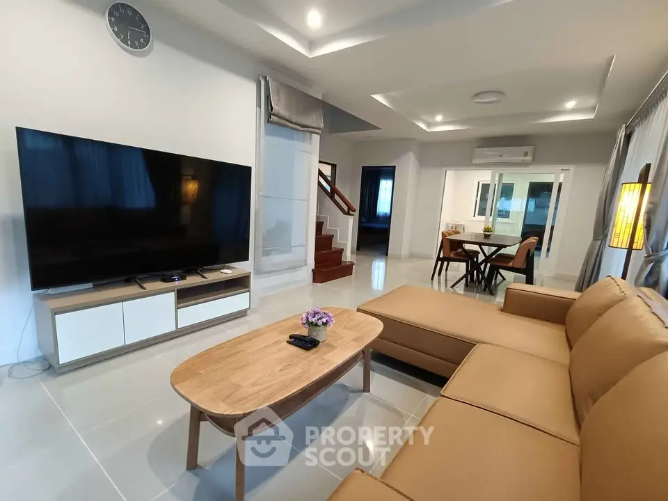 Spacious modern living room with large TV and comfortable seating in a stylish home.