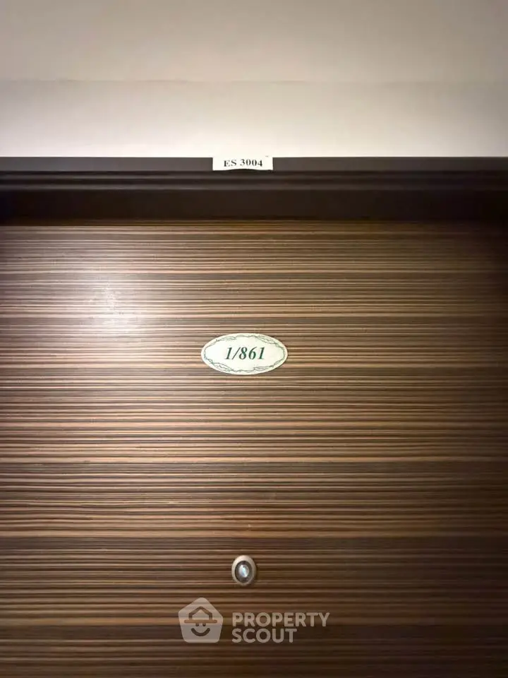 Modern apartment door with sleek wood finish and peephole, showcasing unit number for easy identification.