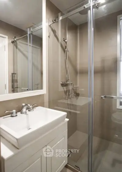 Modern bathroom with glass shower and sleek vanity in contemporary apartment.