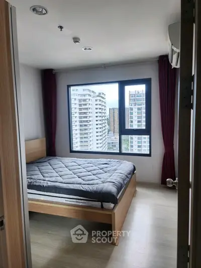 Modern bedroom with large window offering city view in high-rise apartment