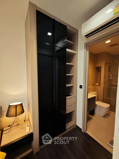 Modern bedroom with sleek black wardrobe and adjacent bathroom