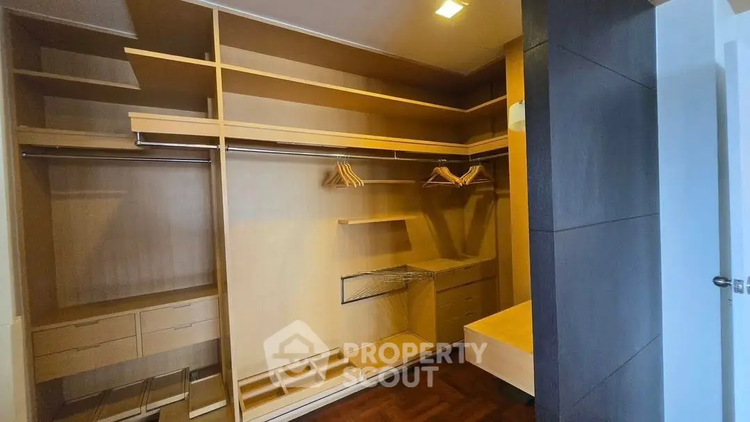Spacious walk-in closet with wooden shelving and ample storage space.