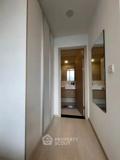Modern hallway leading to a stylish bathroom with sleek fixtures.