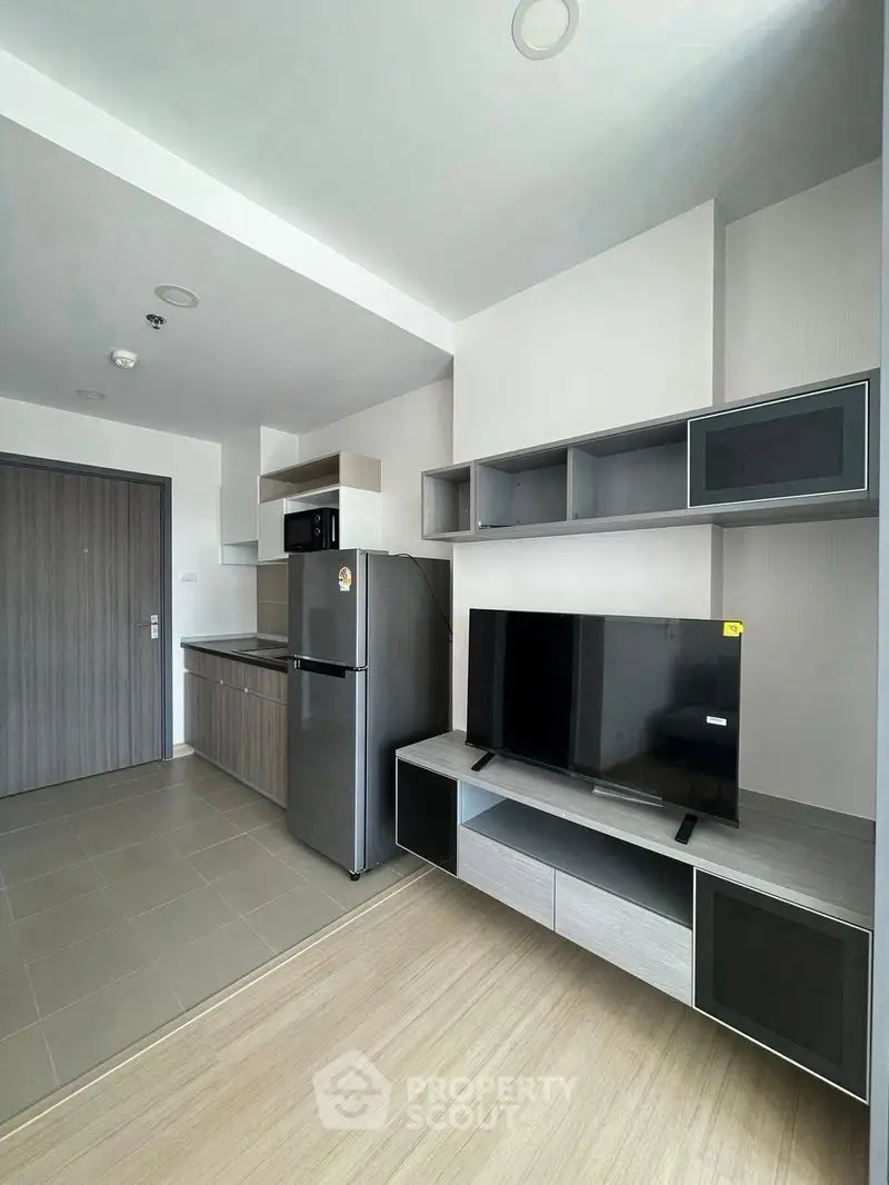 Modern apartment interior with sleek kitchen and stylish living area featuring a flat-screen TV and contemporary decor.