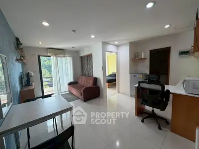 Modern open-layout living room with balcony and kitchen area, featuring sleek furniture and natural light.