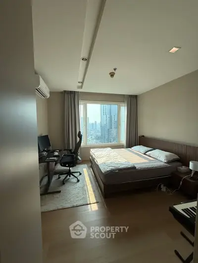 Spacious bedroom with city view, featuring a work desk and modern decor, ideal for urban living.