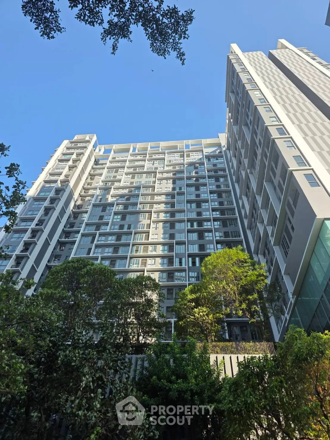 Modern high-rise building with lush greenery and clear blue sky