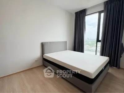 Modern bedroom with large window offering stunning city view and natural light.