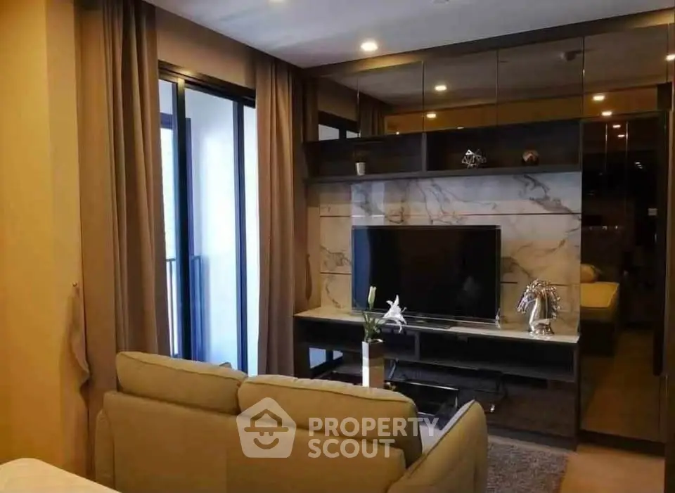 Modern living room with elegant decor and large TV, featuring floor-to-ceiling windows and stylish furniture.