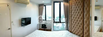 Modern bedroom with city view, featuring a wall-mounted TV and stylish decor.