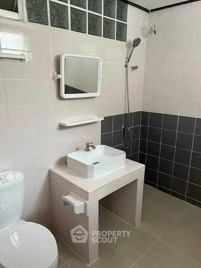 Modern bathroom with sleek fixtures and neutral tiles, featuring a stylish sink and shower area.