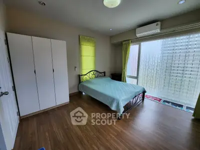 Spacious bedroom with modern decor and large window for natural light.